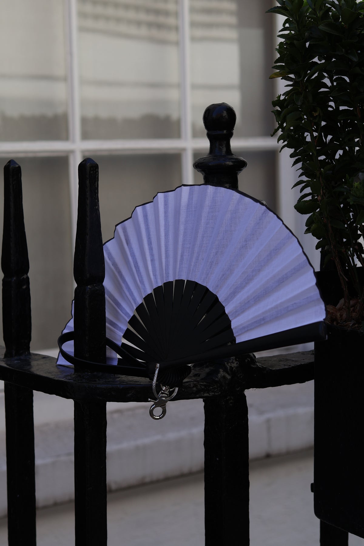 Black and white hand fan displayed on a black railing